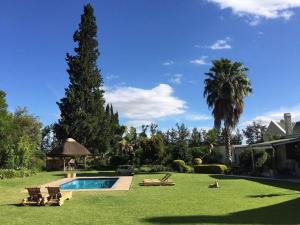 a yard with a pool and chairs and a house at Silos Guesthouse in Addo