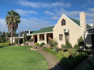 a house with a green roof and a lawn at Silos Guesthouse in Addo