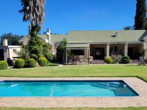 a swimming pool in front of a house at Silos Guesthouse - Travel Addo Group in Addo