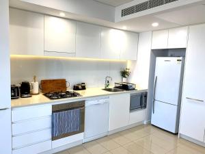 a white kitchen with a stove and a refrigerator at Serenity Peary - Executive 1brm at Darwin Waterfront with Sea Views in Darwin