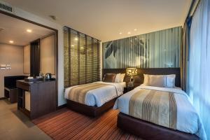 a hotel room with two beds and a mirror at M2 de Bangkok Hotel in Bangkok