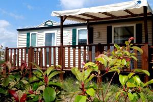 a house with a wooden deck with an awning at Mobilhome «des Salines» * 6 personnes *3 Chambres in Sigean