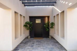 a hallway with a black door and two plants at Phoenix 22nd St home in Phoenix