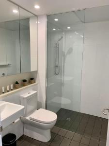 a bathroom with a toilet and a glass shower at Serenity Peary - Executive 1brm at Darwin Waterfront with Sea Views in Darwin