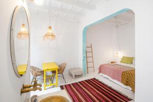 1 dormitorio con cama, mesa y espejo en La Cayena Rooms, en Ciutadella