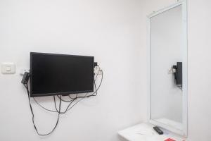a flat screen tv hanging on a white wall at RedDoorz Syariah at Griya Merbotan Demak in Demak