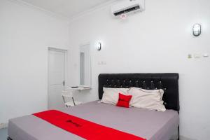 a bedroom with a bed with a red blanket on it at RedDoorz Syariah at Griya Merbotan Demak in Demak