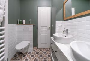 La salle de bains blanche est pourvue d'un lavabo et de toilettes. dans l'établissement Résidence Bains Callou située face aux thermes, à Vichy