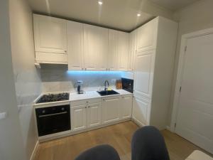 Una cocina con gabinetes blancos, un fregadero y una estufa. en Home № 2, en Kutaisi 12 fotos más