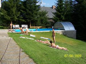 a group of people laying on the grass near a swimming pool at pension Jesen in Benecko