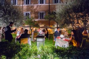 a group of people sitting at tables in a garden at night at Kolbe Hotel Rome in Rome