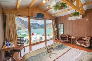 um quarto com uma cama grande e uma janela grande em Luxus Hunza Attabad Lake Resort em Hunza