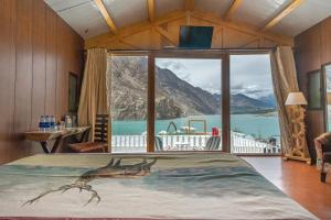 a large bed in a room with a large window at Luxus Hunza Attabad Lake Resort in Hunza