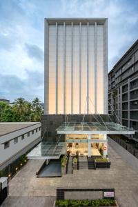 een hoog gebouw met een glazen gevel ervoor bij Ginger Kochi MG Road in Cochin