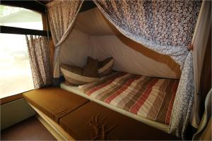 ein kleines Bett in einem Wohnmobil mit Fenster in der Unterkunft DDR Klappfix "FAMILIENPALAST" direkt am Strand in Dranske