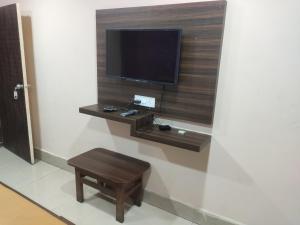 a tv on a wall with a table and a stool at Hotel Cauvery in Visakhapatnam