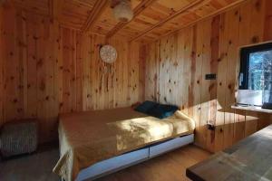 a bedroom with a bed in a wooden wall at Szumi Las 