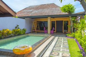 a swimming pool in front of a house at Lavender Villa & Spa in Kuta