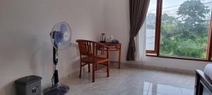 Zimmer mit einem Stuhl und einem Schreibtisch mit einem Ventilator in der Unterkunft Sri Sedana Homestay in Sidemen