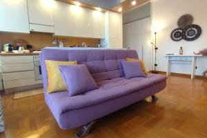 a purple couch in a living room with a kitchen at Gastaldi House, EUR Mostacciano, delizioso flat in Rome