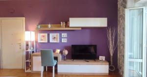 a room with a desk with a television and a purple wall at Gastaldi House, EUR Mostacciano, delizioso flat in Rome