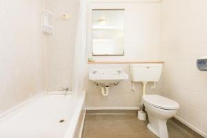 a white bathroom with a toilet and a sink at Alpha Motor Inn in Palmerston North
