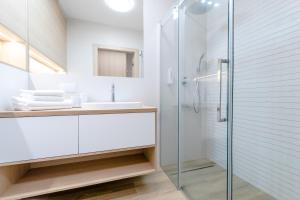 a bathroom with a glass shower and a sink at Sunday SPA in Dziwnów
