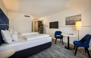 Habitación de hotel con cama, mesa y sillas en ARCOTEL Wimberger Wien, en Viena