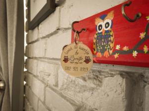 a tag with an owl ornament hanging on a wall at Spruitjie-roer-my-nie in Potchefstroom