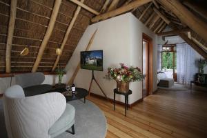 ein Wohnzimmer mit einem Sofa, Stühlen und einem TV in der Unterkunft Adara Palmiet Valley Luxurious Boutique Farm Hotel in Paarl