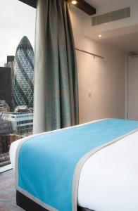 ロンドンにあるモーテル ワン ロンドン タワー ヒルのロンドンのスカイラインを望む客室のベッド1台分です。