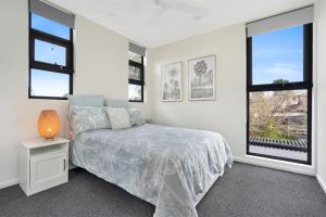 a bedroom with a bed and two windows at Husky Sol in Huskisson