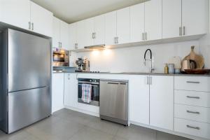 a kitchen with white cabinets and a stainless steel refrigerator at Husky Sol in Huskisson