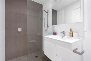 a white bathroom with a sink and a shower at Husky Sol in Huskisson