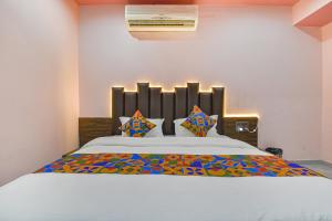 1 dormitorio con 1 cama blanca grande con almohadas coloridas en FabHotel Max Inn en Ahmedabad