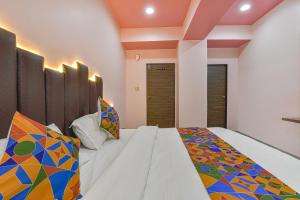 1 dormitorio con 1 cama grande y almohadas coloridas en FabHotel Max Inn, en Ahmedabad