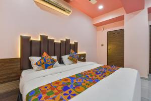 1 dormitorio con 1 cama grande y almohadas coloridas en FabHotel Max Inn en Ahmedabad