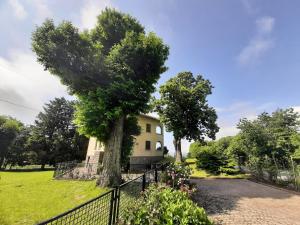 un árbol frente a una casa con una valla en Casa in montagna con giardino privato recintato, en Andrate