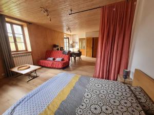 - une chambre avec un lit et un canapé rouge dans l'établissement Aux P'tioux Bonheurs, à Le Noyer