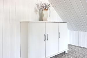 a white cabinet with a vase on top of it at Ferienhaus Windspiel in Kleeden