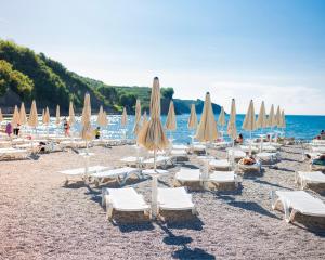 a group of chairs and umbrellas on a beach at Dea Del Mar Apartments in Izola