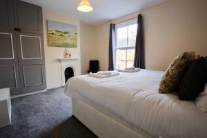 a bedroom with a large white bed with a fireplace at Albemarle House in Taunton