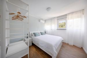 a white bedroom with a bed and a window at Apartment Fani with free private parking in Dubrovnik