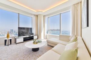 a living room with a couch and a tv and large windows at Ultra Luxury Palm Tower with Shared 5 Star Hotel Facilities in Dubai