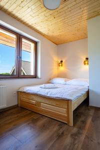 a bed in a room with a wooden ceiling at Bałtyk Park Gąski in Gąski