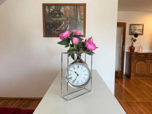 a vase of pink roses sitting on a table with a clock at Ferienwohnung Heidehummel in Lübbenau