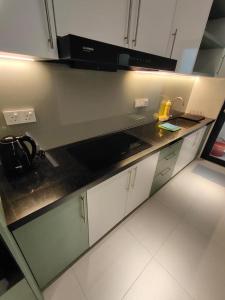 une cuisine avec des placards blancs et un comptoir noir dans l'établissement Reizz Residence By Minsu, à Kuala Lumpur