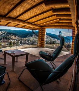 eine Terrasse mit Stühlen, einem Tisch und Aussicht in der Unterkunft Cabana Deac - Luxury Chalet in Vatra Dornei