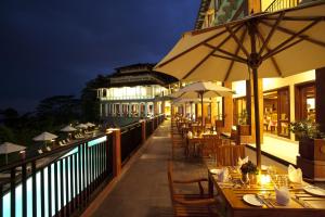 a restaurant with tables and umbrellas on a balcony at night at Amaya Hills Kandy in Kandy