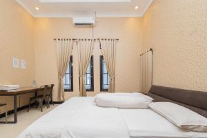 een slaapkamer met een bed, een bureau en ramen bij Boss Residence Serang Mitra RedDoorz in Kumprung